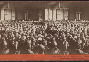 A stereoscopic slide with photos taken from two slightly different angles shows around 100 schoolgirls seated in a large auditorium with several women teachers in the background.