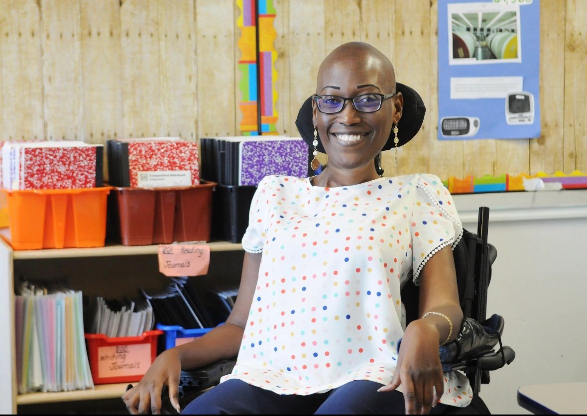 A Black woman sits in a wheelchair inside a classroom
