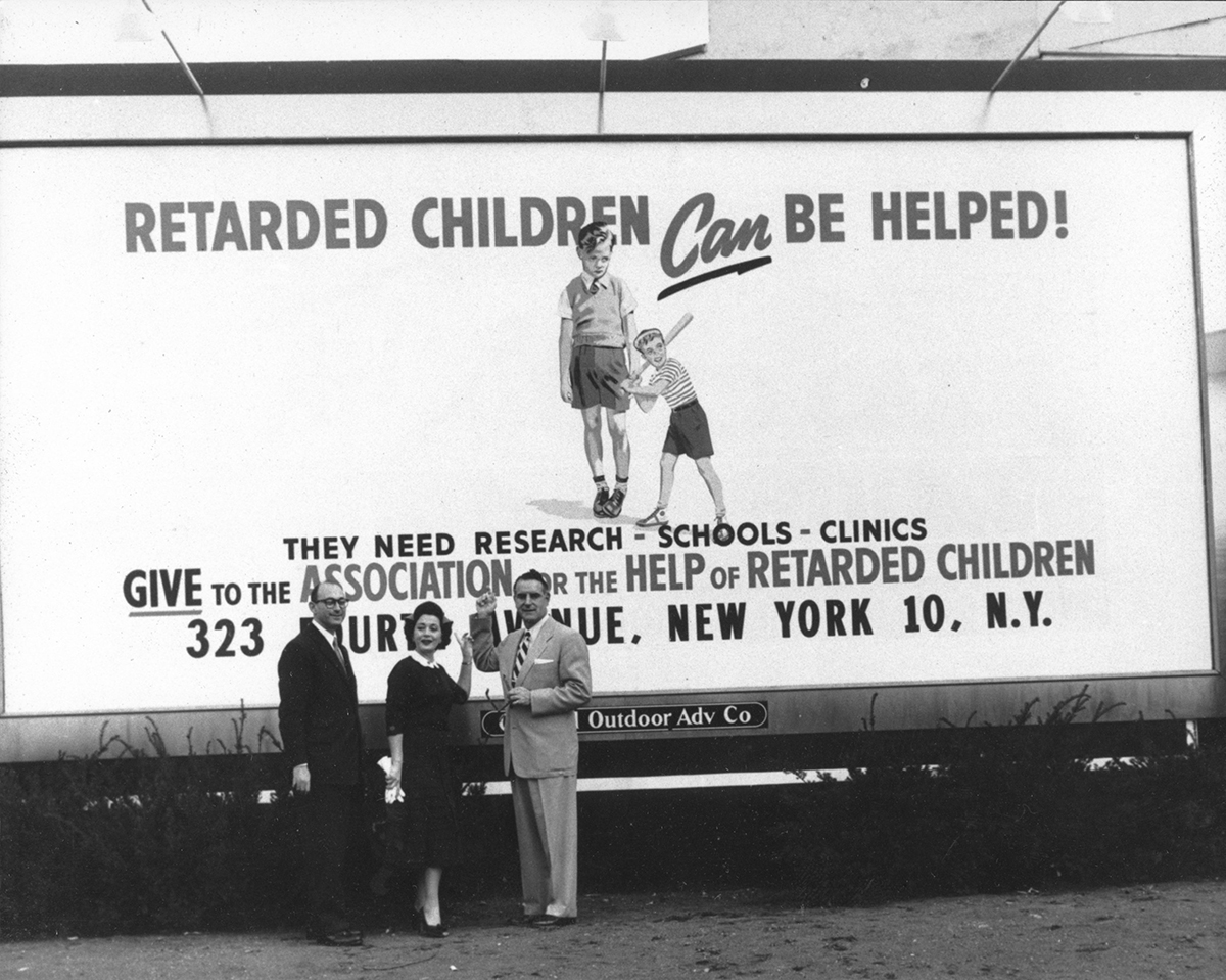 Parent activists pose in front of a billboard that reads, "Retarded Children Can be Helped! They need Research, Schools, Clinics. Give to the Association for the Help of Retarded Children
