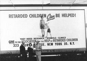 Parent activists in front of a billboard that reads, &quot;Retarded Children Can be Helped! They need Research, Schools, Clinics. Give to AHRC&quot;