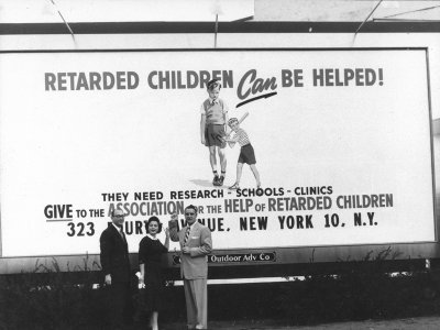 Parent activists pose in front of a billboard that reads, "Retarded Children Can be Helped! They need Research, Schools, Clinics. Give to the Association for the Help of Retarded Children