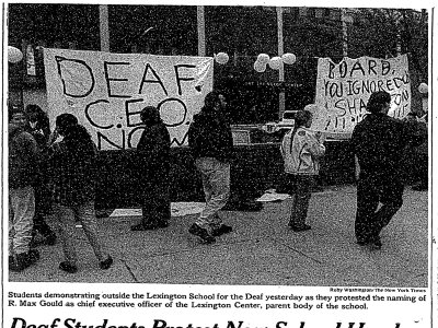 Newspaper article with photo of protestors outside of a school holding signs. One reads, "Deaf CEO Now"