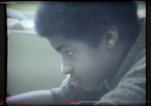 Still image from a news report showing a young black boy in a classroom doing school work