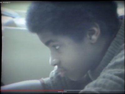 Still image from a news report showing a young black boy in a classroom doing school work