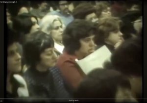 Still image from a news report showing white parents in the audience of a town hall meeting