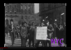 Protestors march, carrying signs